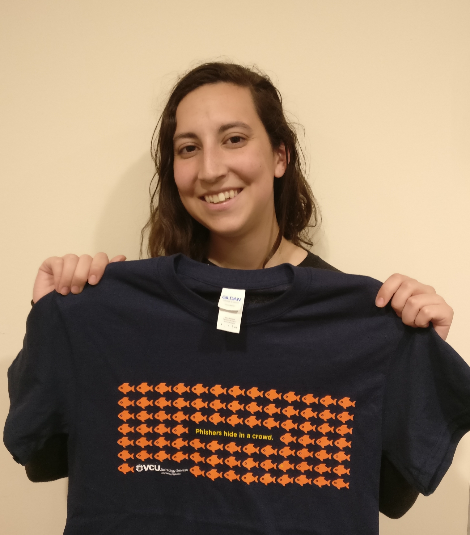 Photo of  Emily Kundrot holding a phishers hide in a crowd tee.